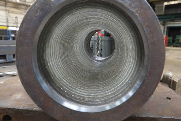 Internal bore of a Synbase CRA weld overlay reducer showing the continuous spiral Inconel 625 overlay bead deposited on the carbon-steel base
